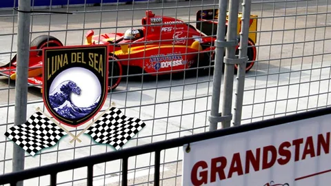 Red and yellow race car beside a Luna Del Sea crest.